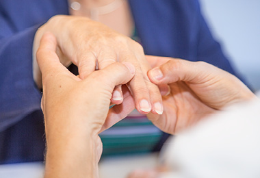 Close up van zorgprofessional die hand van patiënt bekijkt