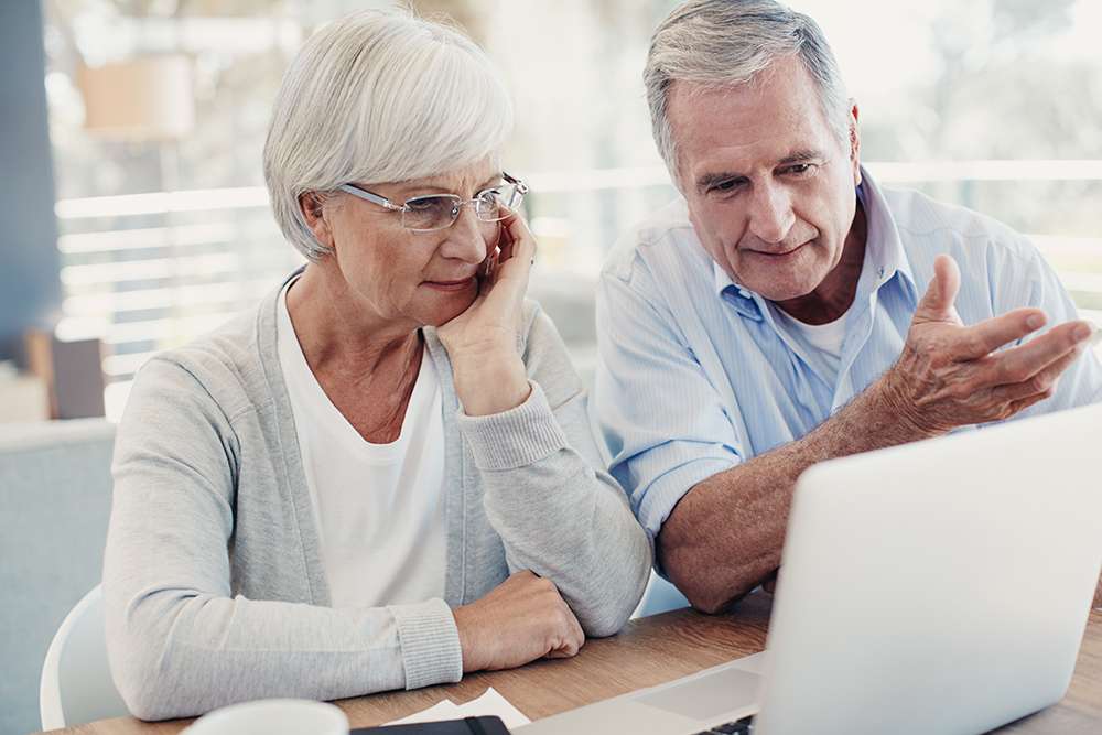 Oudere man en vrouw werken aan laptop